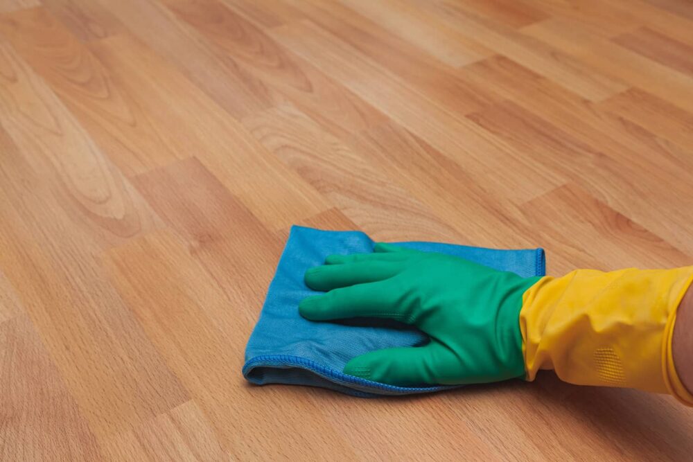 Using a microfiber cloth to clean the wood flooring with Fabuloso.